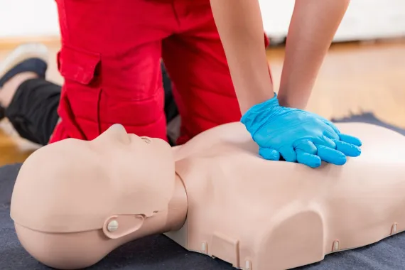 A person practicing CPR on a training dummy.