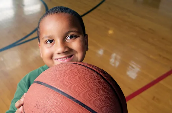 A smiling child holding a basketball.