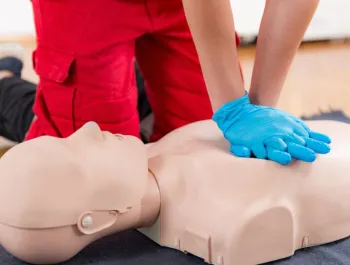 A person practicing CPR on a training dummy