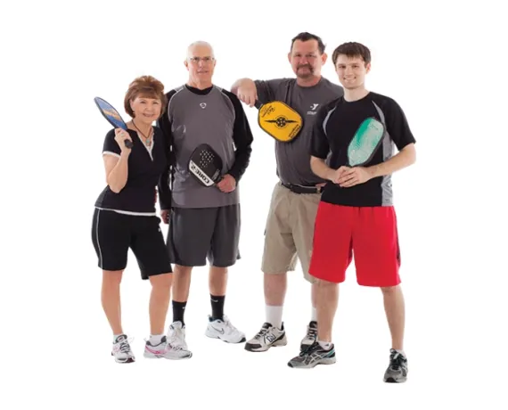 A group of 4 people holding pickleball rackets.